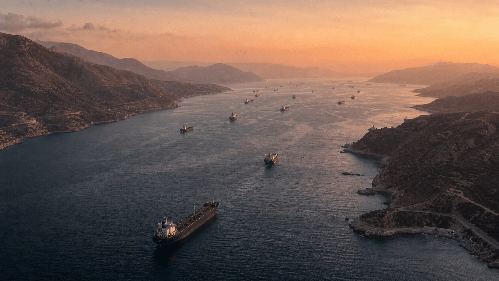 Cargo ships in a narrow strait at sunset